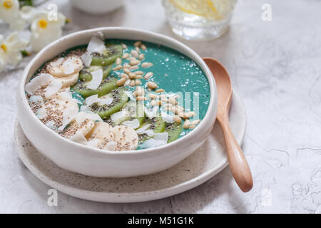 La prima colazione La spirulina frullato di cocco ciotola e rabboccato con scaglie di noce di cocco e frutti di bosco Foto Stock