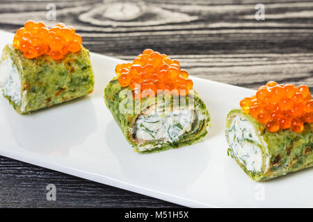 Frittelle di spinaci e caviale rosso su sfondo di legno Foto Stock