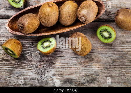 Ripe kiwi in un piatto di legno su un sfondo di legno. Mangiare sano. Foto Stock