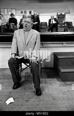 Uomo in sedia a rotelle prendendo parte al canto solista concorrenza al piccolo eisteddfod nel village hall Trawsfynydd Gwynedd Wales UK Foto Stock