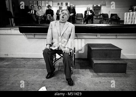 Uomo in sedia a rotelle prendendo parte al canto solista concorrenza al piccolo eisteddfod nel village hall Trawsfynydd Gwynedd North Wales UK Foto Stock