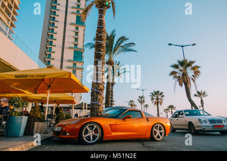 Una Chevrolet Corvette C6 LS3 arancione metallizzato è parcheggiato fuori una caffetteria a Beirut, Libano, un pomeriggio di sole Foto Stock