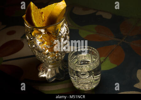Mezcal messicano in un bicchiere accanto alla tazza di cristallo con fette di arance in stile messicano piastrelle Foto Stock