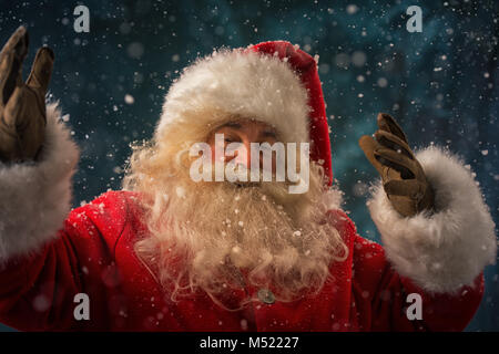 Santa Claus rendendo la magia di notte sotto la neve all'aperto Foto Stock