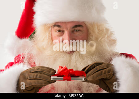 Ritratto di felice Babbo Natale regalo azienda dispositivo nelle sue mani con nastro Foto Stock