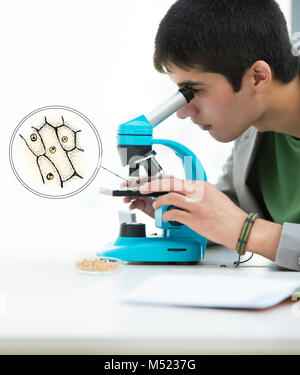 Gli studenti delle scuole superiori. Bel giovane studente maschio del peering attraverso il microscopio nella classe di scienze Foto Stock