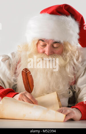 Real Santa Claus iscritto lista di doni o di rispondere ai bambini le lettere sulla vecchia carta di scorrimento, isolati su sfondo bianco Foto Stock