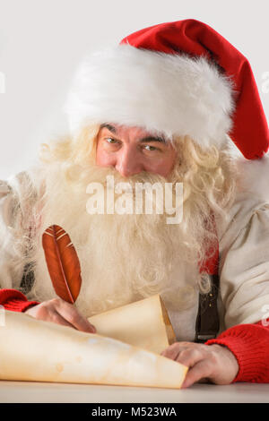 Real Santa Claus iscritto lista di doni o di rispondere ai bambini le lettere sulla vecchia carta di scorrimento, isolati su sfondo bianco Foto Stock