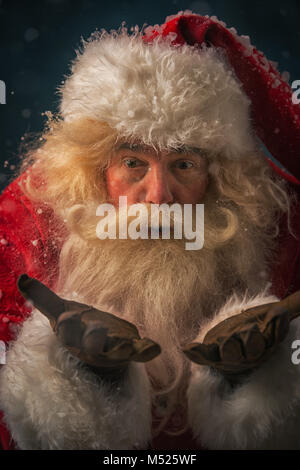 Santa Claus rendendo la magia di notte sotto la neve all'aperto Foto Stock