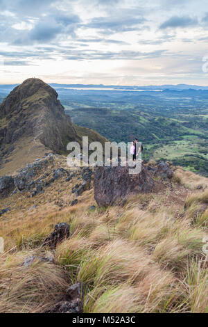 Gli escursionisti quasi alla sommità del Cerro Pelado in Costa Rica, la mattina presto girato con il terreno roccioso e erba essiccata al vento. Foto Stock