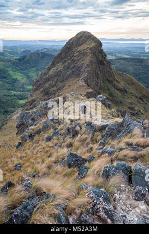 Gli escursionisti quasi alla sommità del Cerro Pelado in Costa Rica, la mattina presto girato con il terreno roccioso e erba essiccata al vento. Foto Stock