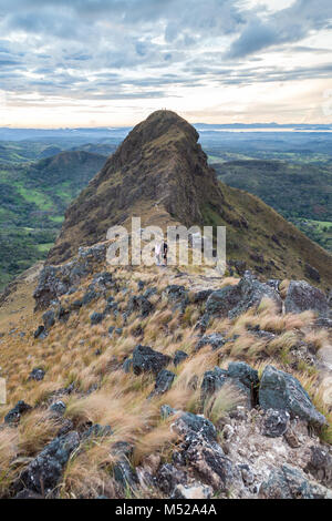 Gli escursionisti quasi alla sommità del Cerro Pelado in Costa Rica, la mattina presto girato con il terreno roccioso e erba essiccata al vento. Foto Stock