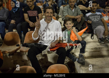 Un padre e figlio di guardare il calcio siriano Cup finale, 2017, dalle gabbie. Molti genitori hanno detto che sono ancora troppa paura di portare i loro figli a giochi. Il calcio siriano cup finale è stata giocata tra Al-Wahda Al-Karamah e squadre di calcio. Nonostante il conflitto in corso in un paese lacerato dalla guerra di Siria, il calcio siriano cup finale è stata ospitata nella città capitale di Damasco che è sotto il governo siriano di controllo con molti locali per gli appassionati di calcio hanno assistito alla partita. Foto Stock