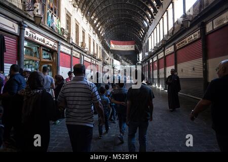 Gli amanti dello shopping a piedi passato Bakdash, una famosa gelateria che è stato aperto in Al-Hamidiyah Souq nella città vecchia di Damasco dal 1885. Nonostante il conflitto in corso in Siria, la vita nel governo-held parti di Damasco continua in modo relativamente pacifico. Damasco, la città capitale di lacerata dalla guerra Siria, è per la maggior parte sotto il controllo del funzionario del governo siriano guidato dal Presidente Bashar al-Assad. Foto Stock