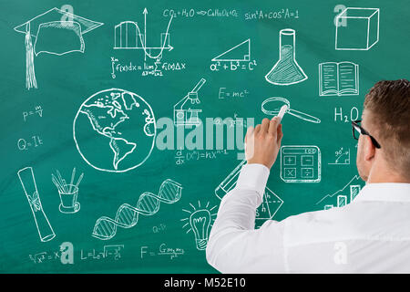 Vista posteriore di un insegnante di scienze scrivere formule su Verde Chalk Board Foto Stock