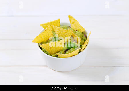 La vaschetta del guacamole con mais tortilla chips su sfondo bianco Foto Stock