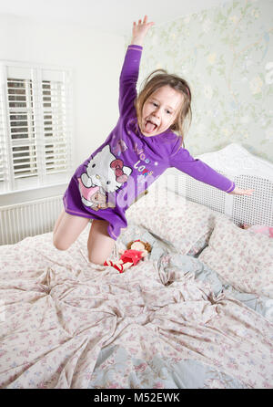 4 anno vecchia ragazza di saltare sul letto dei genitori Foto Stock