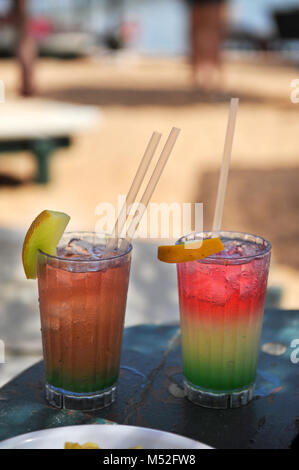 Due multi-i cocktail colorati sullo sfondo della spiaggia. Due bicchieri con cocktail colorato su una spiaggia vicino al mare Foto Stock