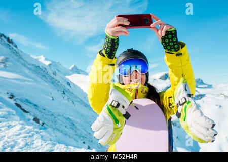 Foto di sport donna che indossa il casco rendendo selfie sullo sfondo di colline innevate Foto Stock