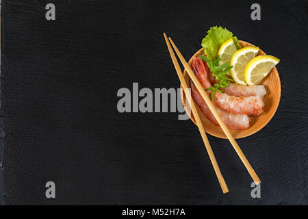 I gamberi su un piatto di legno con bacchette di legno Foto Stock