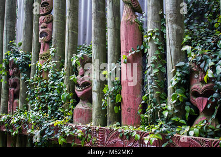 Maori maschere intagliate con foglie intorno Foto Stock