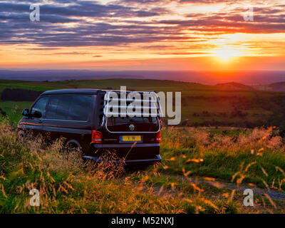 VW California camper parcheggiato per la notte in una libera posizione glamping occupanti godendo il bel tramonto durante vicino Pym poltrona del parco auto Foto Stock
