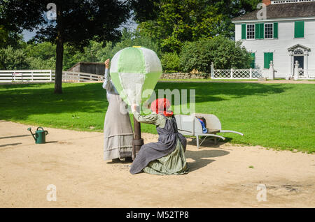 Due donne in costume di Old Sturbridge Village, riempimento a casa in mongolfiera ad aria calda in un antico giocattolo di dimostrazione. Foto Stock