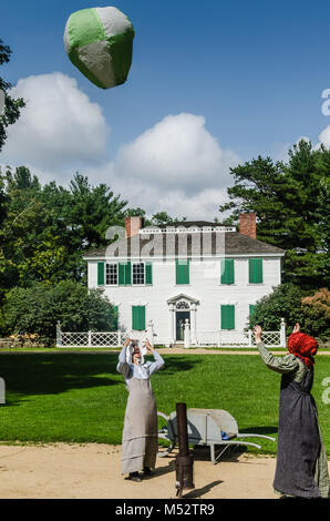 Due donne in costume di Old Sturbridge Village, riempimento a casa in mongolfiera ad aria calda in un antico giocattolo di dimostrazione. Foto Stock