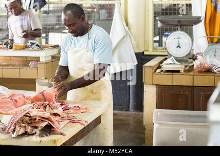 Bridgetown, Barbados - Gennaio 31th, 2018: un lavoratore a Bridgetown Mercato del pesce è la preparazione di pesce Salmone in vendita. Foto Stock