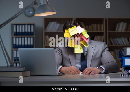 Uomo d'affari che soggiornano in ritardo per ordinare le priorità Foto Stock