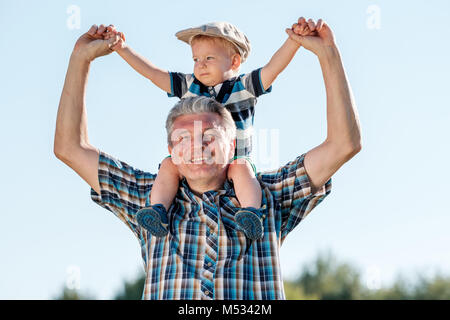 Nonno porta nipote toddler boy sulle sue spalle Foto Stock