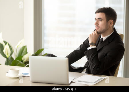Pensieroso il business leader seduti alla scrivania in ufficio Foto Stock
