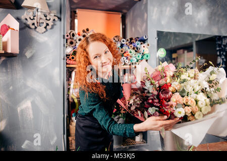 Colpo di bella ragazza con bellissimi fiori sul luogo di lavoro Foto Stock