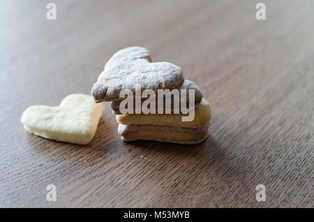 Close-up di biscotti a forma di cuore che giace sul tavolo di legno sfondo Foto Stock