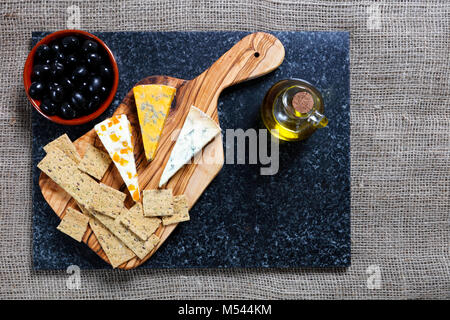 Cibo scuro - Stiltons blu e blu Shropshire formaggi su un'oliva pannello di legno Foto Stock