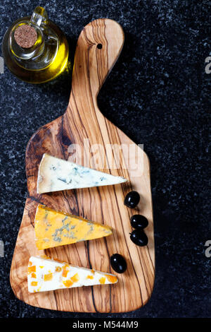 Cibo scuro - Stiltons blu e blu Shropshire formaggi su un'oliva pannello di legno Foto Stock