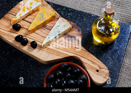 Cibo scuro - Stiltons blu e blu Shropshire formaggi su un'oliva pannello di legno Foto Stock