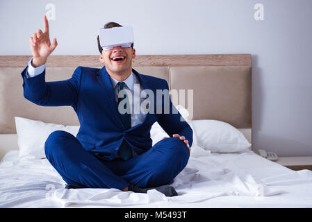 Imprenditore indossando una realtà virtuale auricolare in camera da letto Foto Stock