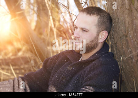 Un riflessivo uomo barbuto nella foresta tramonto Foto Stock
