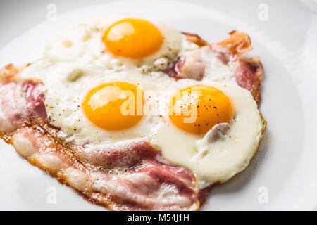 Prosciutto e uova. Uova e pancetta. Uovo salato con pepe sulla piastra bianca. Prima colazione inglese. Foto Stock