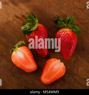 Rosso fresco Fragole Shot direttamente dall'alto in Studio su marrone sullo sfondo di legno Foto Stock