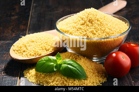 Ciotola di couscous crudo su un tavolo di legno. Foto Stock