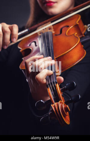 Bella giovane donna a suonare il violino su sfondo scuro Foto Stock