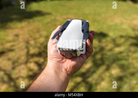 Un DJI Mavic aria drone ripiegato in un mans mano per mostrare le dimensioni del drone Foto Stock