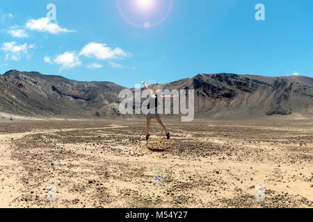 Ragazza il salto nel Cratere Sud, Tongiriro Crossing Foto Stock