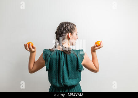 Bella donna sta con la schiena e trattiene le arance in mani Foto Stock