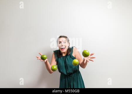 Ragazza ridere su uno sfondo bianco gettando frutti Foto Stock