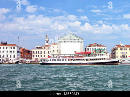 Vista diurna turistiche alla barca vicino alla Riva degli Schiavoni waterfront. Architettura storica degli edifici sullo sfondo. Luminoso cielo blu con nuvole Foto Stock