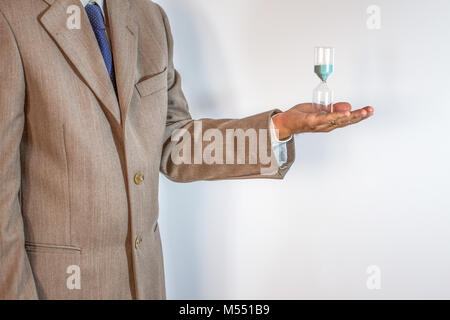 Imprenditore tenendo una clessidra isolati su sfondo bianco - Il tempo è denaro concetto. Foto Stock