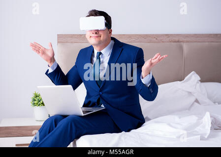 Imprenditore indossando una realtà virtuale auricolare in camera da letto Foto Stock